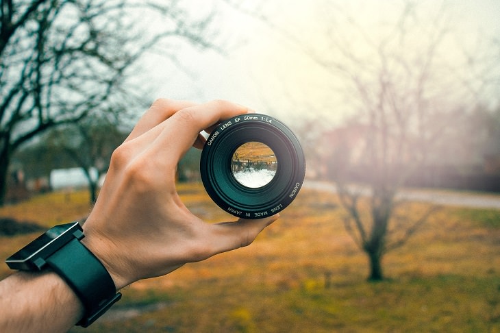 Surprising brain facts: Woman holding a camera lens and pointing it at the scenery in front of her