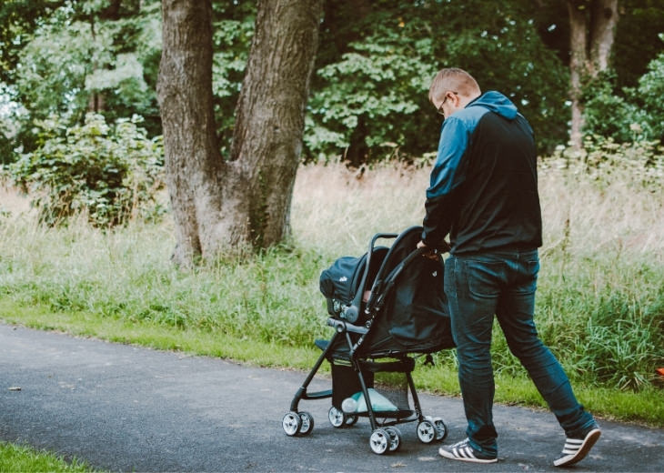 Actions and habits that cause lower back pain: Person hunched over pushing a baby stroller