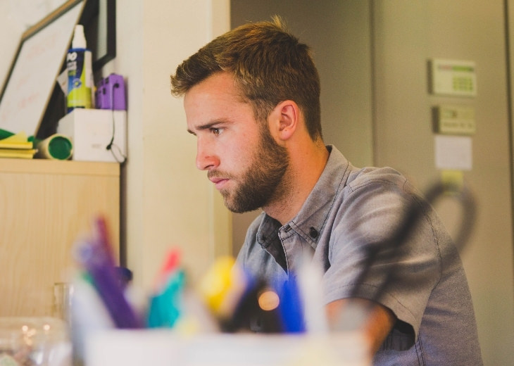 Actions and habits that cause lower back pain: Person sitting at work desk with hunched back