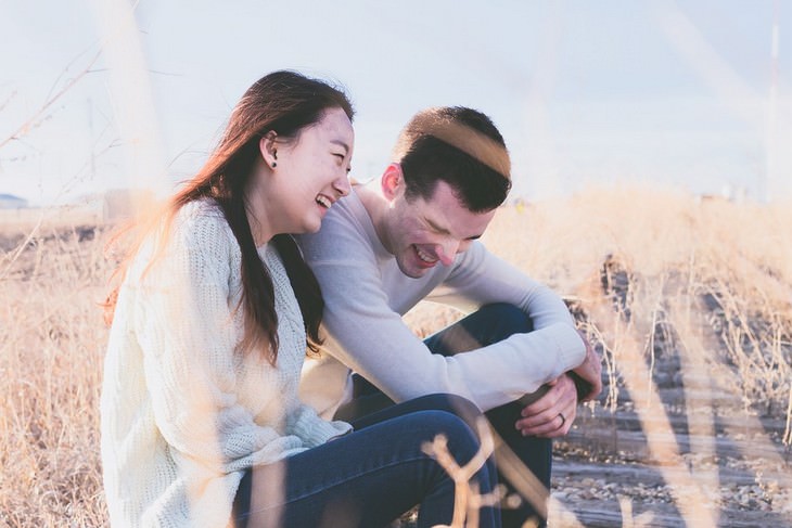 A man and a woman sitting happily next to each other in a wheat field