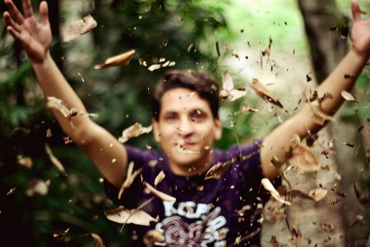 A man throwing dry leaves into the air