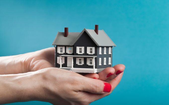 Are you an attentive or talkative person: A woman holds a model of a house