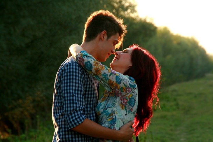 A man and a woman hugging and smiling in a forest background