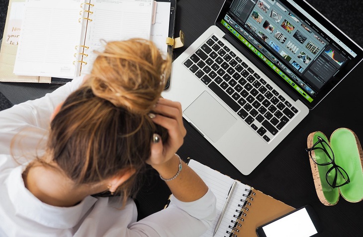 Complaints in Relationships: A woman sits in front of a laptop holding her head