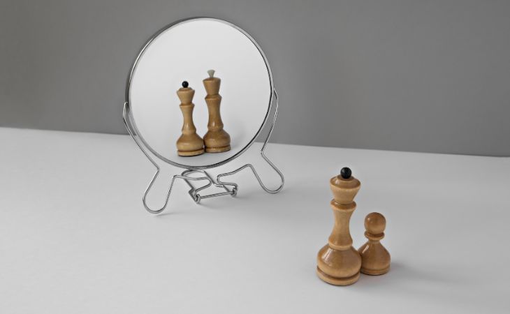 How to Beat a Narcissist: Chess pieces in a mirror, with a pawn appearing as a king in the reflection