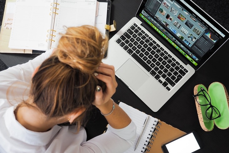 Methods to overcome insomnia: A woman holding her head and sitting next to an open laptop