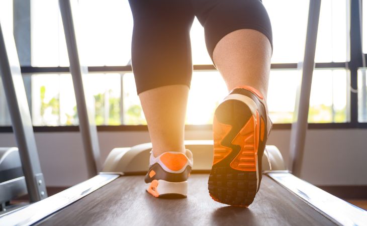 באיזו שעה כדאי להתאמן למניעת סיכונים בריאותיים בעודף משקל: רגליים של אישה כבדת משקל על הליכון