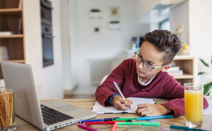 child writing while looking at computer