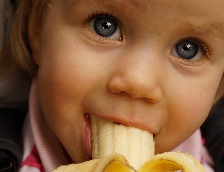 Tips to prevent bedwetting: Girl eating a banana