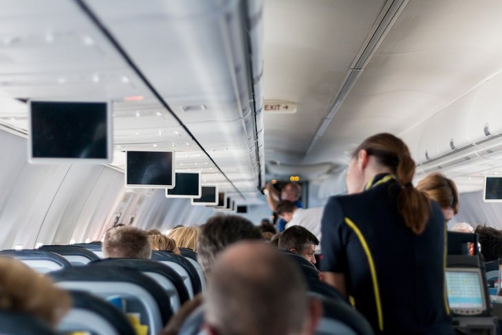 Things to avoid on a flight: flight attendant standing near passengers on a plane