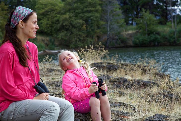 Parenting Styles: Mother and daughter laughing together in nature with binoculars in their hands