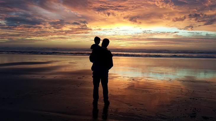 Questions to ask your kids: Silhouette of a dad holding a child by the hand on the beach at sunset