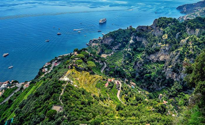 The Amalfi Coast in Italy: High view of green cliffs and boats in the sea