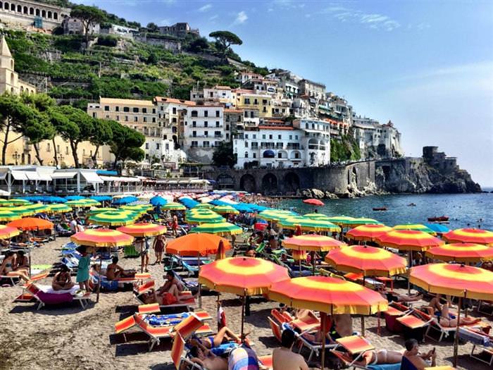 The Amalfi Coast in Italy: People lying under sun umbrellas on the beach