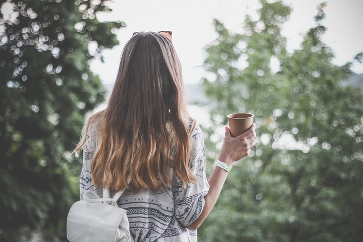 Uses of eucalyptus oil: Woman with abundant hair holding a cup, back to the camera