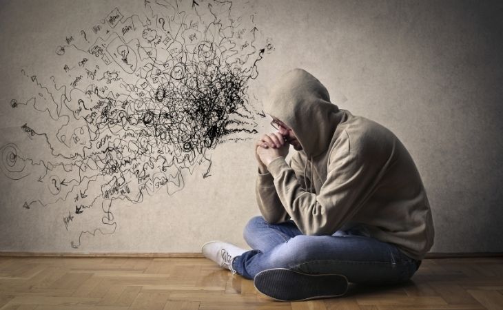 How to Break a Cycle of Negative Thoughts: A man sits on the floor thinking negative thoughts