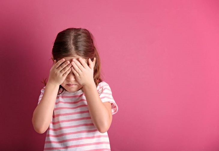 Signs of mental disorders in children: a girl covering her eyes with her hands