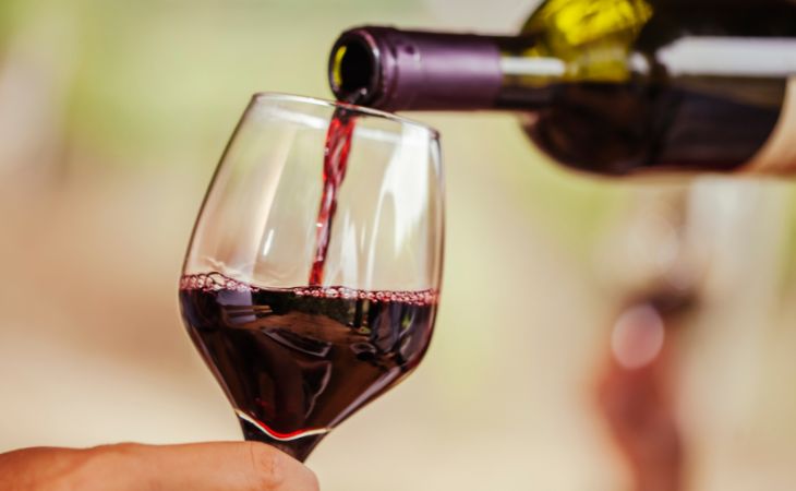 Is a glass of red wine a day healthy: Pouring red wine from a bottle