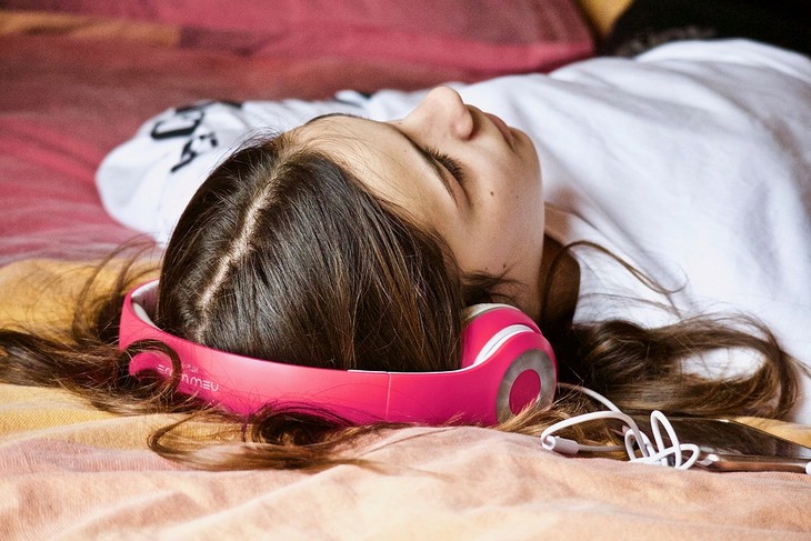 Problems caused by smartphone use in children: girl lying on a bed with headphones