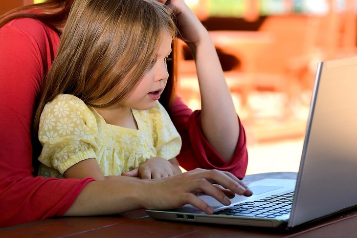 Problems caused by smartphone use in children: girl and mom sitting together and looking at a computer