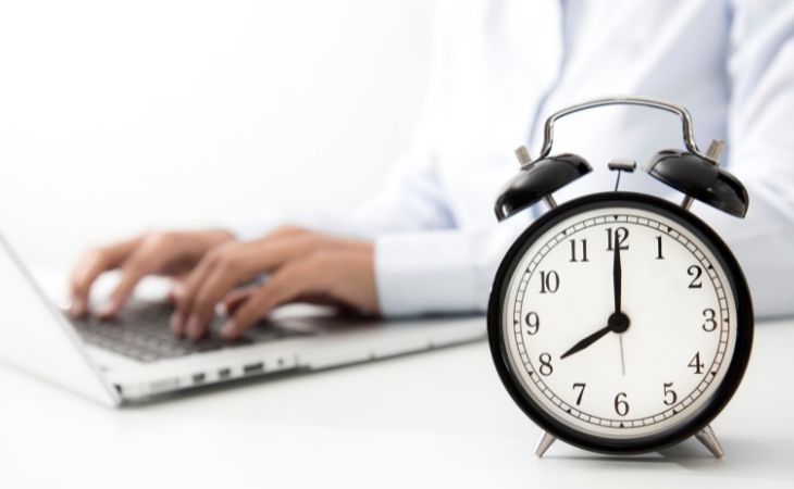 Study on working hours and risk of death: hands typing with a clock in front of them