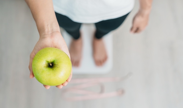 Apple cider vinegar and weight loss: Person with scale with apple tree