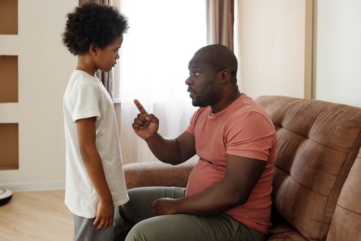 Psychological Tricks for Parents: Father talking to his son while sitting opposite him and scolding him