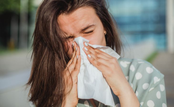 Why you shouldn't drink coffee with cold medications: Woman blowing her nose