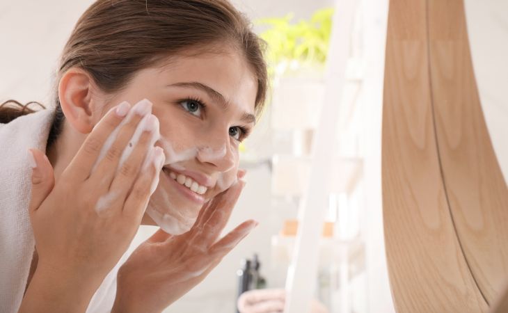 At what age can children use cosmetics and skincare products: A young woman cleansing her face with a foam cleanser