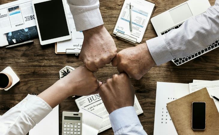 13 steps to success: people bumping fists over a worktable