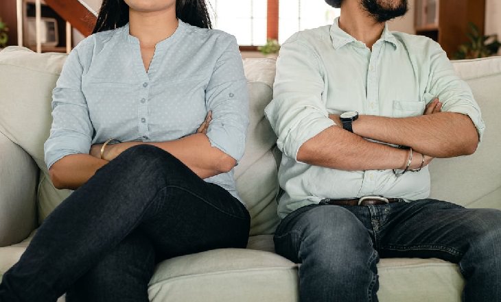 Casal sentado de braços cruzados e discutindo