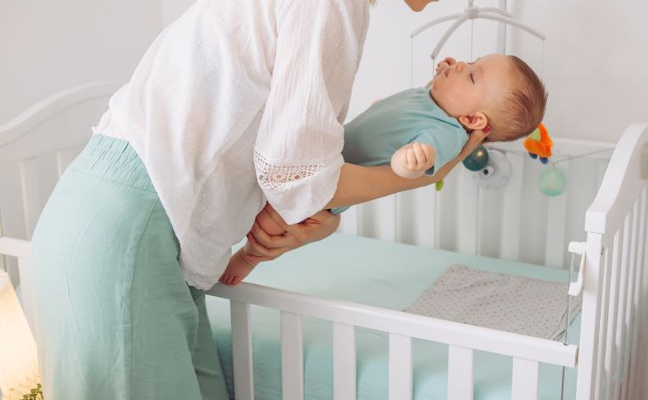 How parents harm their children’s sleep: a mother placing a sleeping baby in a crib