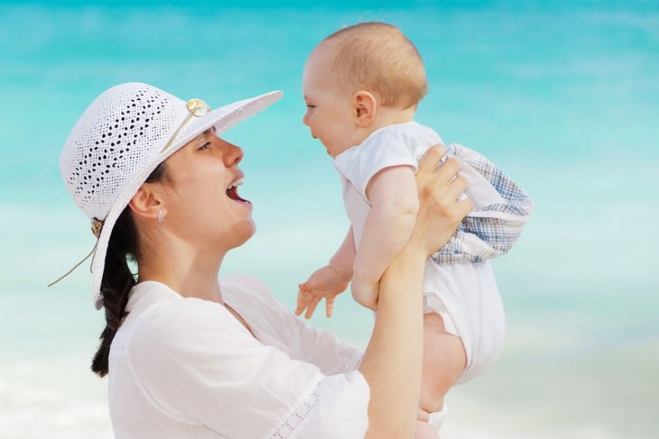 A mother holding her baby with the sea in the background