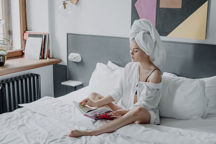 Mistakes in Hair Brushing: A woman sitting on a bed with a towel wrapped around her hair