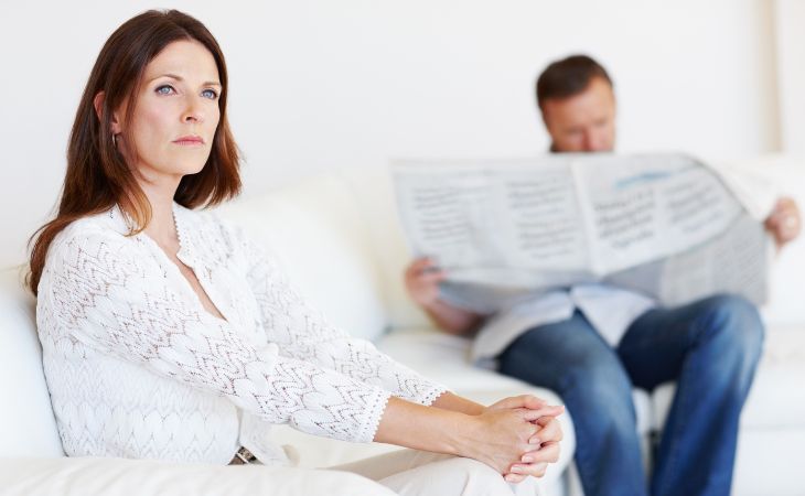 What to do if you feel lonely in marriage: Husband reading a newspaper and wife staring into the distance