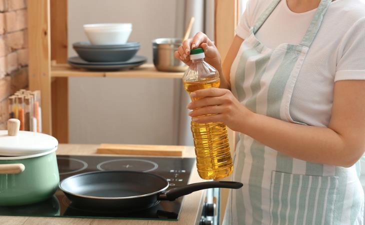 Things not to keep near the stove: Woman with cooking oil