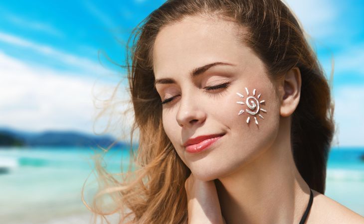 How to choose sunscreen: A woman with sunscreen in the shape of a sun on her face