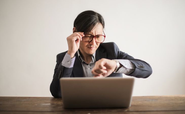 What are Micro-Breaks: A man sitting in front of a laptop looking at his wristwatch