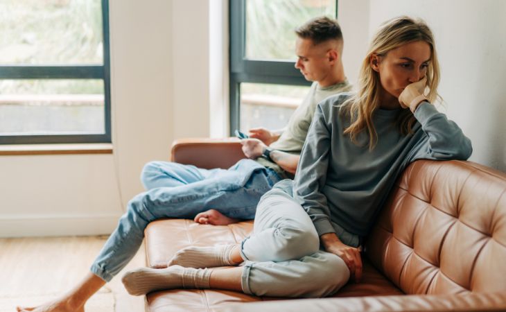 Signs that an emotionally unavailable person loves you: A frustrated woman and a man sitting beside her looking at his phone