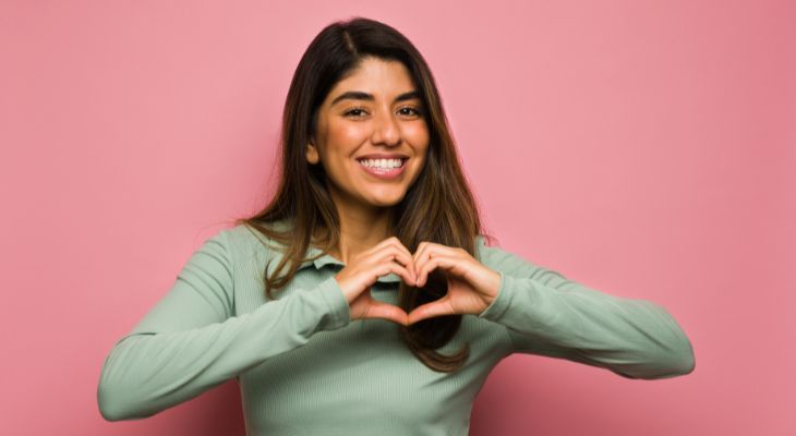 How to identify emotions and the message they convey: A smiling woman making a heart with her hands
