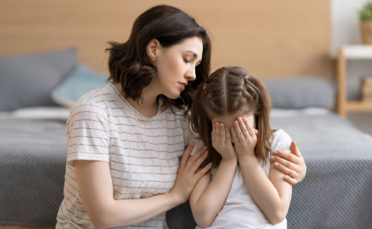How to know if your child is hiding their feelings and what to do about it: A mother comforting a girl