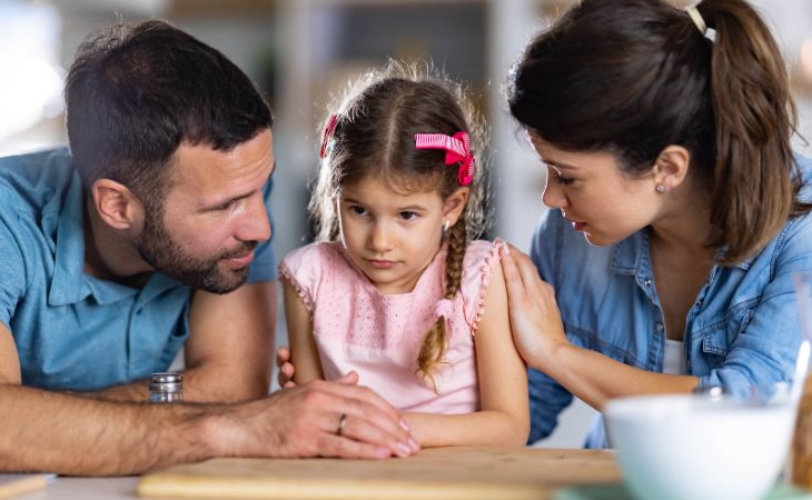 How to know if your child is hiding their feelings and what to do about it: Parents talking with their daughter
