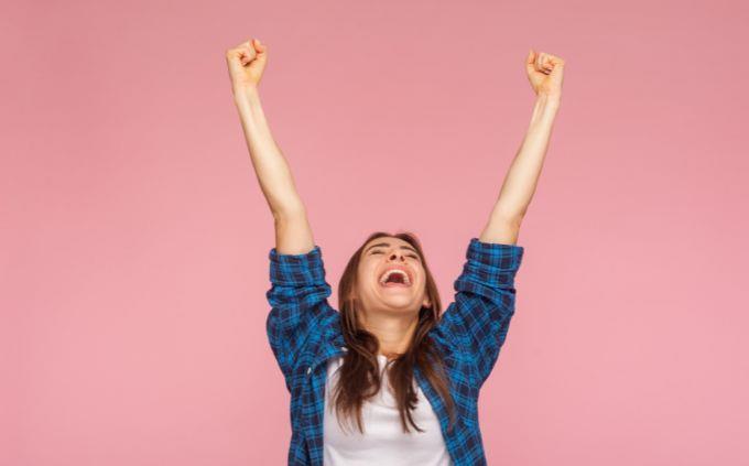 Trivia Women influence history: A woman raises hands happily into the air