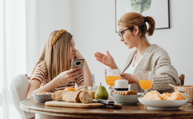 How to prevent children from becoming addicted to screens: A mother talking with her daughter who is using a mobile phone