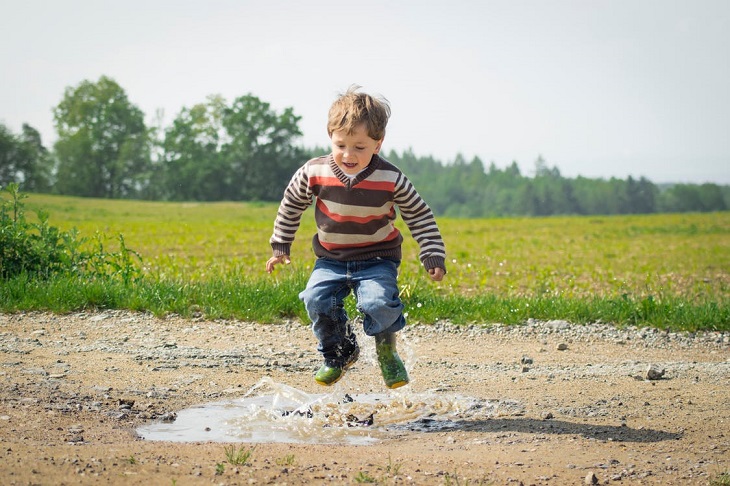 Small parental gestures for children: A child jumping into a puddle near grass