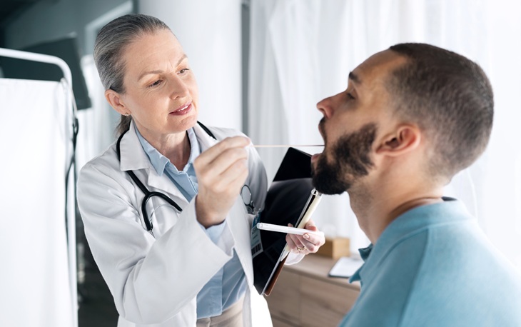 Tonsil cancer: a female doctor examining a man's tonsils