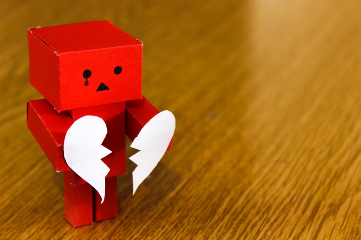 Fears of people-pleasers: a sad red paper doll holding a broken heart