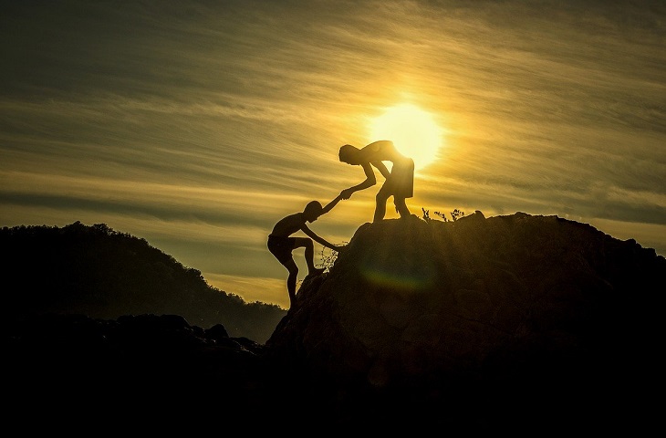 Fears of people-pleasers: a boy preventing another boy from climbing a hill at sunset
