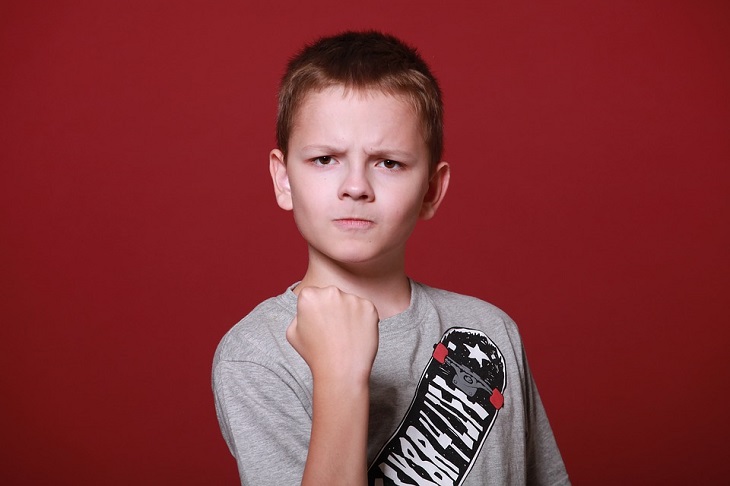 Fears of people-pleasers: a child with an angry face showing a fist